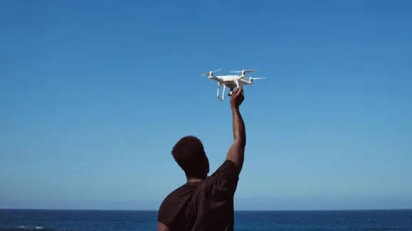 Person holding a drone beside the ocean